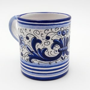 May include: A white ceramic mug with a blue and white floral design. The mug has a blue rim and a blue handle.