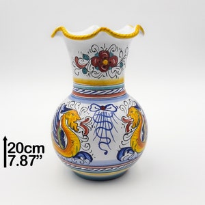 May include: White ceramic vase with a scalloped rim, decorated with yellow, blue, red, and green floral and dragon designs. The vase is 7.87 inches tall.