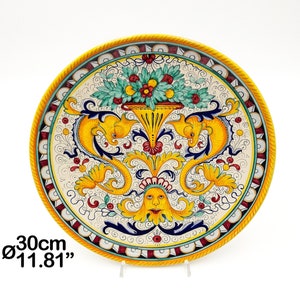 May include: A yellow, white, blue, red and green ceramic plate with a floral design and two yellow seahorse figures. The plate is 30cm in diameter.