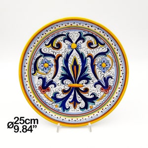 Peut inclure: Une assiette en céramique blanche avec un motif floral bleu et jaune. L'assiette a un diamètre de 25 cm.