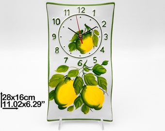 May include: White ceramic clock with a green border and a lemon design. The clock face has black hands and green numbers. The clock is 11.02 inches by 6.29 inches.