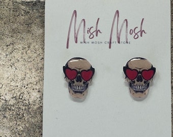 May include: A pair of skull earrings with red heart-shaped sunglasses. The earrings are handmade in Arizona and are sold by Mish Mosh.