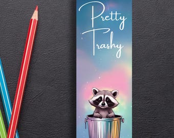 May include: A blue and pink galaxy-themed bookmark with a raccoon sitting in a silver trash can. The text "Pretty Trashy" is written in white on the bookmark.