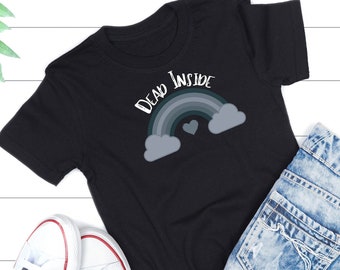 May include: Black t-shirt with a rainbow and the text "Dead Inside" printed on it. The shirt is laid out on a white wooden surface with a pair of white sneakers and blue denim shorts.