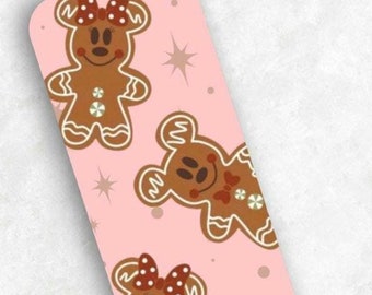 May include: A rectangular bookmark with a pink background featuring a pattern of gingerbread bear characters. The gingerbread bears have brown bodies, white accents, and red bowties or bows. White star shapes are scattered across the background.