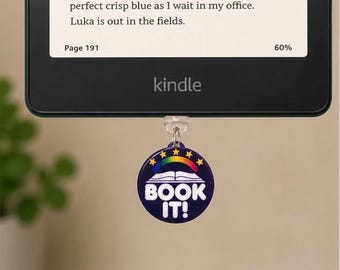 May include: A black Kindle e-reader with text on the screen, displaying "Page 191" and "60%". A dark blue circular charm with a rainbow, stars, and the words "BOOK IT!" hangs below the device.