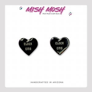 May include: A pair of black heart-shaped earrings with the text "ELDER EMB" in white lettering.