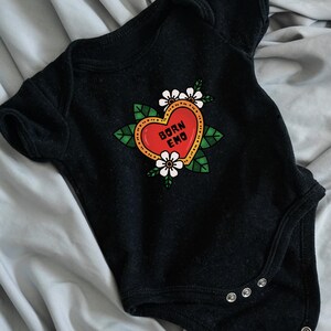 May include: Black baby onesie with a red heart graphic that says "Born Emo" in white text. The heart is surrounded by green leaves and white flowers.