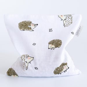 May include: White fabric bag with a repeating pattern of cartoon hedgehogs in brown and tan. The bag has a triangular shape and a small tag that reads "LOOLAY".