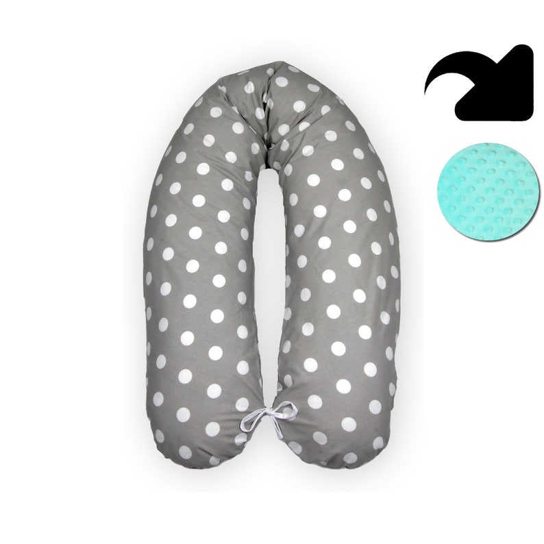 May include: A gray and white polka dot pregnancy pillow with a white tie in the middle. The pillow is shaped like a U and is designed to support the body during pregnancy.