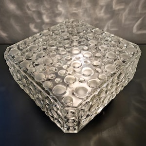 Puede incluir: Una lámpara de techo cuadrada de cristal transparente con una superficie texturizada de pequeñas burbujas redondas.