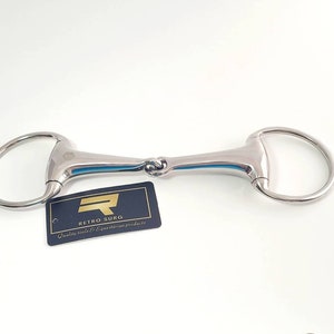 May include: A silver horse bit with a jointed mouthpiece. The bit is designed for use with a horse's bridle. The bit is made of metal and has a smooth finish. The bit is a popular choice for riders who want a bit that is gentle on the horse's mouth.  Quality tools & equestrian products - Retro Surg