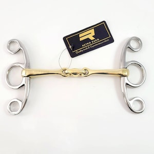 Pode incluir: Um freio de cavalo dourado e prateado com uma embocadura de dupla articulação e três anéis de cada lado. O freio é etiquetado com "RETROSURG" e "Quality tools & Equestrian products".