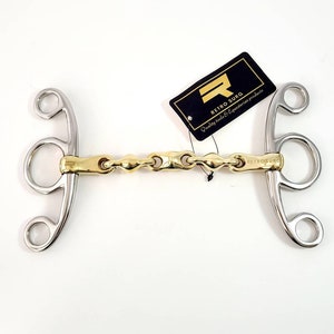 Op de afbeelding: Een zilveren en gouden paardenbit met een kettinglink. Het bit heeft aan elke kant drie ringen en het merk "Retro Surg" is zichtbaar op het bit.