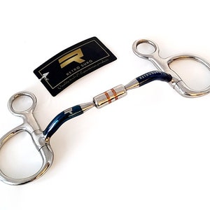 Può includere: Un morso a snaffle blu e argento con un rullo in rame. Il morso è realizzato da Retro Surg, un'azienda che produce prodotti equestri di qualità.