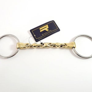 May include: A gold-coloured horse bit with a twisted link design and two silver rings. The bit is labelled "Retro Surg" and "Quality tools & Equestrian products".