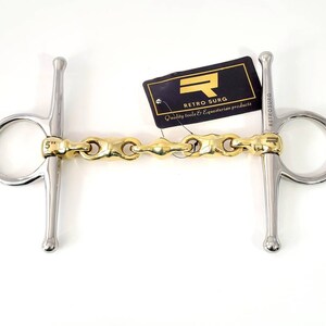 Pode incluir: Um freio de cavalo de prata e ouro de 5 polegadas com uma embocadura de elo de corrente. O freio é etiquetado como "Retro Surg" e "Quality tools & Equestrian products".
