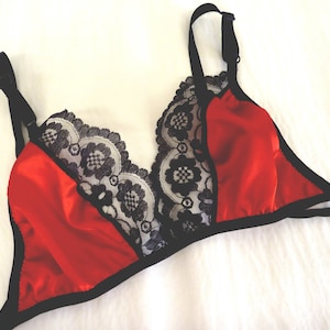 Op de afbeelding: Een rode satijnen en zwarte kant lingerie bh met verstelbare bandjes.