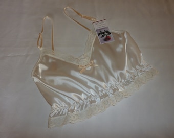 May include: A white satin top with a lace trim and a bow at the neckline. The top has adjustable straps and is made of a soft, silky fabric.