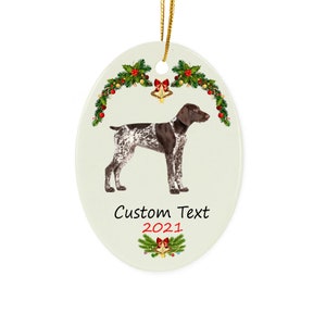 May include: Oval-shaped Christmas ornament featuring a German Shorthaired Pointer dog with brown and white markings. The ornament has a gold string for hanging, with festive holly and bell accents. Text reads "Custom Text 2021".