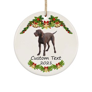 Op de afbeelding: Een bruine en witte hond staat voor een kerstkrans met rode en groene versieringen. De tekst "Custom Text 2021" staat onder de hond.
