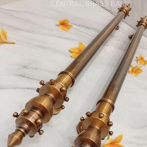 Op de afbeelding: Twee antieke messing deurgrepen met een puntige punt en decoratieve accenten. De grepen zijn gemaakt van massief messing en hebben een verweerde afwerking.