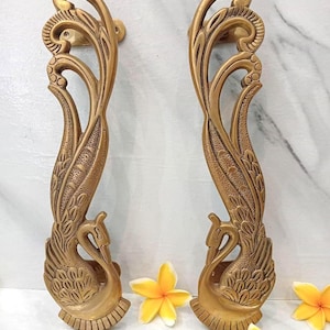 May include: Two vertical brass door handles featuring an intricate peacock design with textured feathers and a curved neck. The metal has a matte gold finish. The text CENTRAL BRASS BALI is visible at the top center of the image.