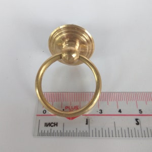 May include: A gold-toned ring pull handle with a round base. The handle is approximately 1 inch in diameter.