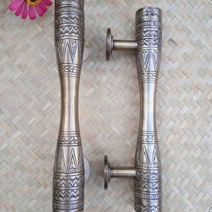 May include: Two ornate brass door handles with intricate geometric designs. The handles are cylindrical and have a textured surface.