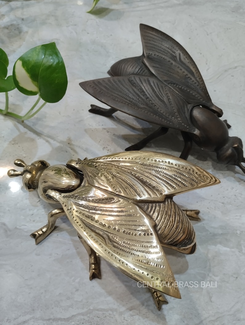 May include: Two brass fly sculptures. One fly is gold and the other is dark brown. The gold fly is detailed with small dots and lines. The dark brown fly is detailed with lines. The gold fly
Bee ashtray brass

Vintage bee ashtray

Golden bee figurine

Brass insect ashtray

Bee decor for shelves

Brass bee home decor

Bee collectible souvenir

Bee shaped ashtray gift

Unique brass ashtray

Insect themed ashtray
Bee gift for him

Bee lover gift idea

Small gift for smoker

Bee collectible gift