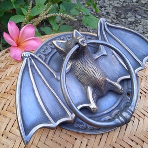 Halloween house accessory
Gothic home decor
Solid brass door knocker
Handmade bat knocker
Dark fantasy decor
Unique gift door knocker
Gothic bat home decor
Halloween-themed gift, Unique bat wings door knocker for Halloween decor
Vintage bat wing door