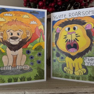 Puede incluir: Dos tarjetas de felicitaci&oacute;n con leones de dibujos animados. La primera tarjeta tiene un le&oacute;n con un fondo de puesta de sol y el texto "Thank You". La segunda tarjeta tiene un le&oacute;n con la boca abierta y el texto "You're ROARsome!"