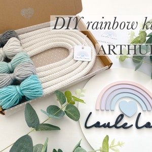 May include: A craft kit for making a rainbow, presented in a box with a white rope and grey and teal yarn. A wooden rainbow decoration with a heart and the text "Laula Love" is also visible.