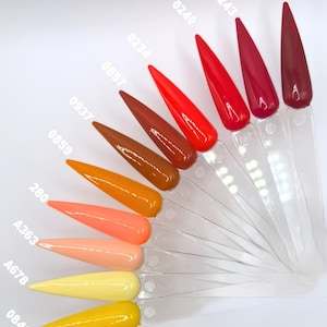 May include: A collection of nail polish color swatches in various shades of red, orange, and yellow. Each swatch is labeled with a unique code, such as "0240" and "0840", and is mounted on a clear plastic stick. The colors range from bright coral to deep burgundy.