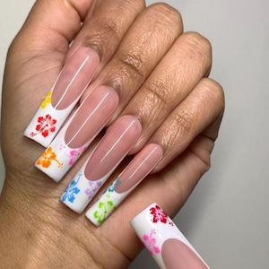 May include: Long, square-shaped artificial nails with a French manicure design. The white tips feature colorful floral patterns in red, pink, yellow, blue, and green. The nails have a glossy finish and are shown against a neutral background.