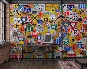 Può includere: Un muro ricoperto da un collage di segnali stradali colorati, tra cui la Route 66, i limiti di velocità e i segnali autostradali. Una scrivania con un computer e una lampada si trova di fronte al muro. La stanza ha un muro di mattoni e un pavimento in legno.