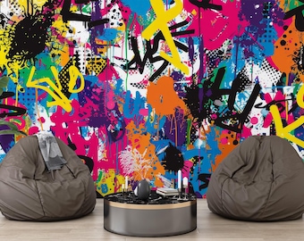 Puede incluir: Un colorido mural de arte graffiti abstracto con salpicaduras de amarillo, rosa, naranja y negro. Dos pufs marrones se encuentran frente al mural, con una pequeña mesa redonda y una planta en maceta. Una estatua decorativa se encuentra a la derecha.