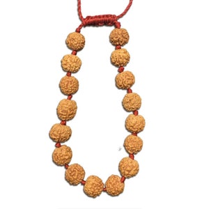 May include: A brown mala bracelet with 18 beads and a red cord. The beads are round and have a textured surface.