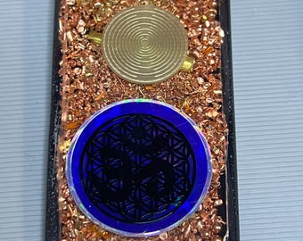 Peut inclure: Un pendentif rectangulaire avec un cadre noir contenant des éclats métalliques couleur cuivre. Il présente un disque circulaire doré avec des anneaux concentriques et un insert circulaire bleu irisé affichant un motif géométrique noir.