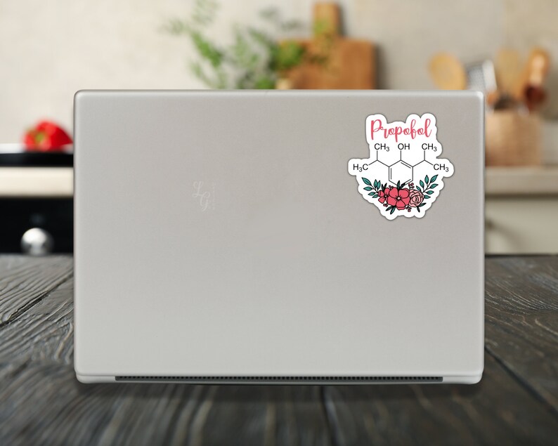 May include: A white laptop with a sticker on the back. The sticker features a chemical structure with the word "Propofol" written above it. The chemical structure is surrounded by pink and green flowers.