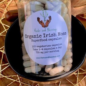 May include: A clear glass bottle filled with white capsules labeled "Herbs and Blessings Organic Irish Moss Superfood capsules 120 vegetarian capsules Take 1-4 capsules a day 735 ng per serving www.HerbsandBlessings.com"