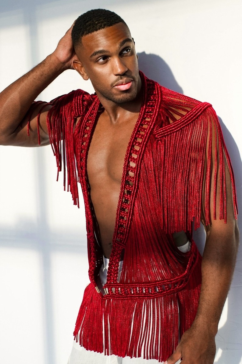 May include: A red crocheted vest with fringe detailing. The vest has a deep V-neck and is open in the front.