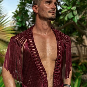 May include: A maroon crocheted top with fringe detailing. The top has a deep V-neckline and is sleeveless.