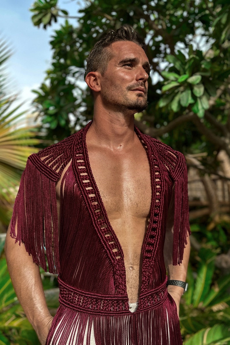 May include: A maroon crocheted top with fringe detailing. The top has a deep V-neckline and is sleeveless.