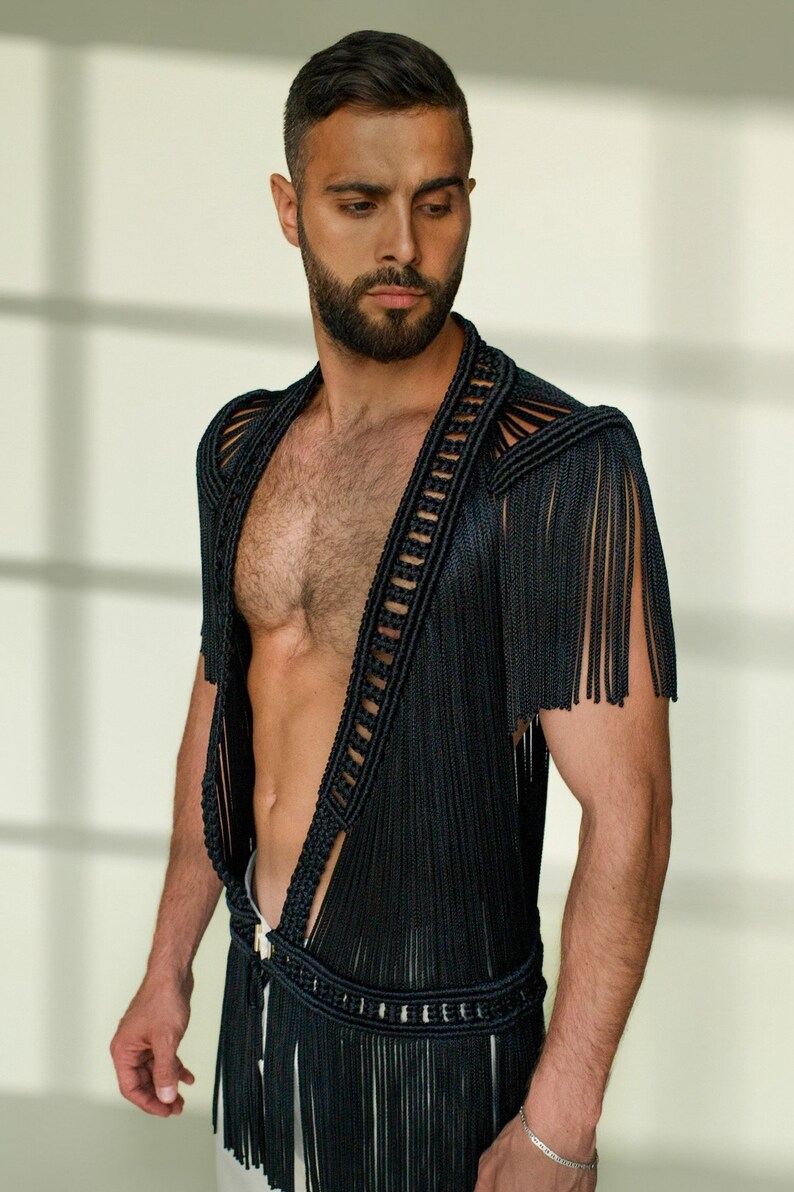 May include: A black fringe vest with a deep V-neckline. The vest is made of a woven material and has a fringe trim around the edges.