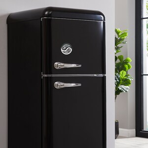 May include: A black retro-style refrigerator with two doors and chrome handles. A sticker with the text "Catch Vibes" is on the top door.