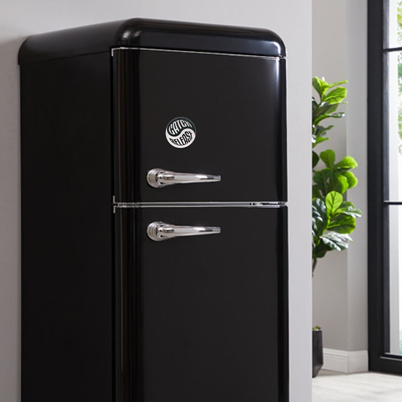 May include: A black retro-style refrigerator with two doors and chrome handles. A sticker with the text "Catch Vibes" is on the top door.