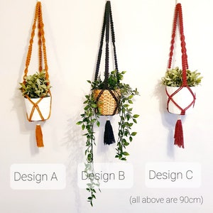 以下が含まれることがあります： 異なる色のコードとタッセルが付いた、3つのマクラメ製のプラントハンガー。ハンガーの長さは90cmで、鉢植えの植物と一緒に表示されています。