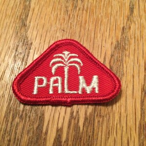 May include: Red triangular patch with white embroidered palm tree and the word "PALM" in white.