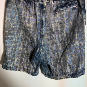 May include: Blue denim shorts with a tie-dye pattern. The shorts have a drawstring waist and a back pocket.